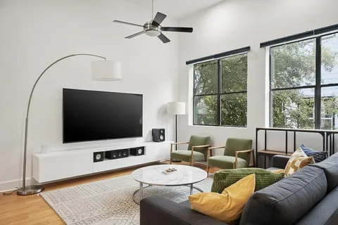 a living room with furniture a flat screen tv and a large window