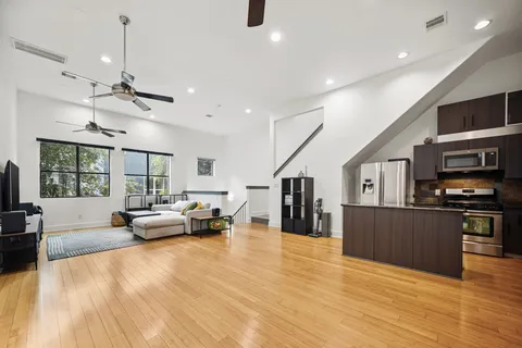 a living room with stainless steel appliances furniture and a flat screen tv