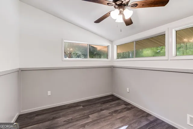 a view of an empty room with a window and wooden floor