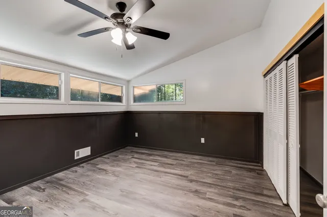 a view of an empty room with a window and kitchen view