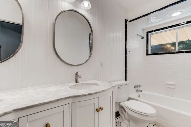 a bathroom with a granite countertop toilet a sink and a mirror
