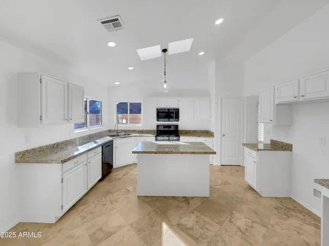 a large kitchen with stainless steel appliances granite countertop a stove a sink and a refrigerator