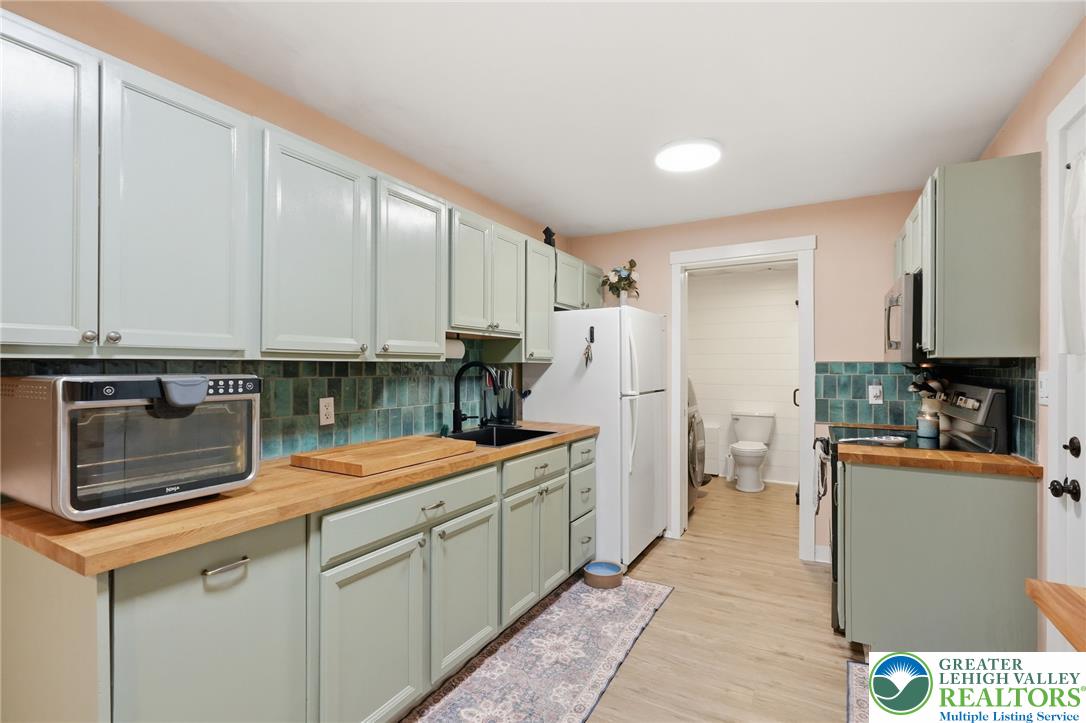 9033 Loop Road Slatington, PA 18080 - Photo 21 of 53 A compact kitchen with light green cabinetry and wood countertops offers efficient meal preparation space.