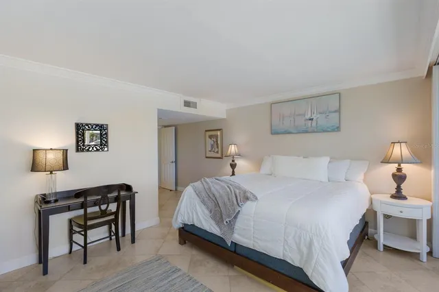 a bedroom with a bed a lamp on desk and a window