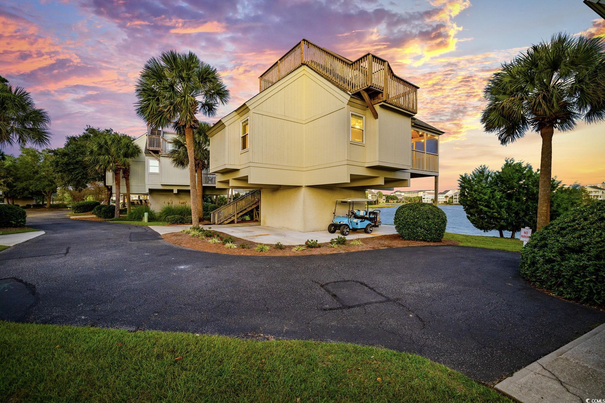 Modern home featuring a balcony, stairs, driveway, and a carport