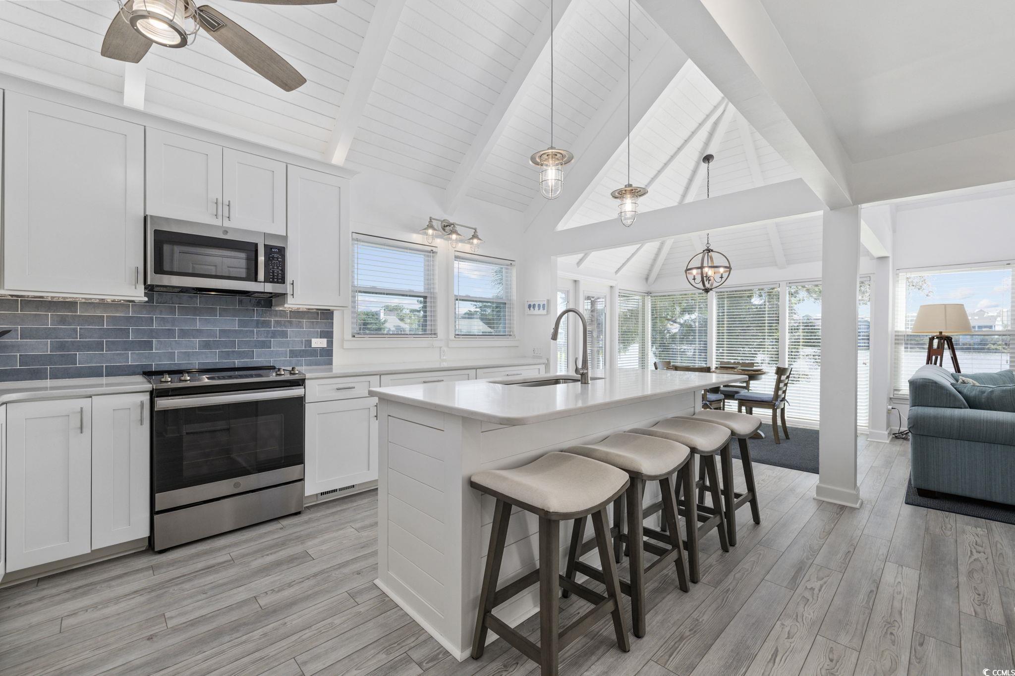 27 Riptide Lane Pawleys Island, SC 29585 - Photo 40 of 40 Kitchen featuring appliances with stainless steel finishes, backsplash, open floor plan, beam ceiling, and white cabinets