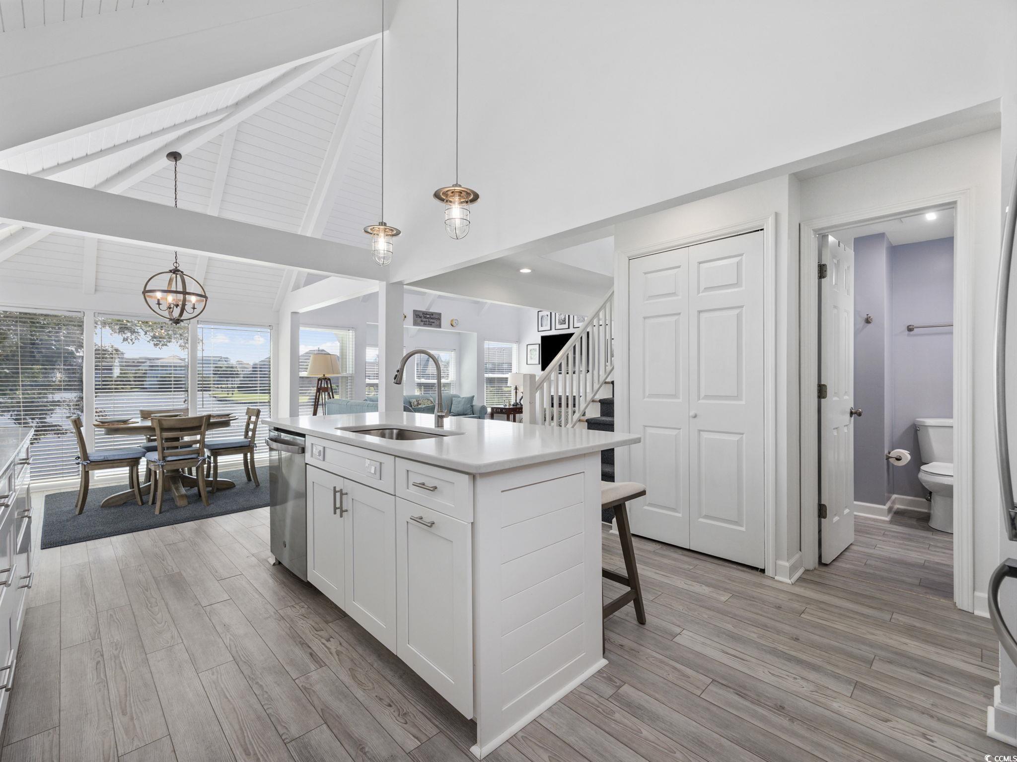27 Riptide Lane Pawleys Island, SC 29585 - Photo 14 of 40 Kitchen with pendant lighting, high vaulted ceiling, white cabinets, a kitchen island with sink, and light wood-style floors