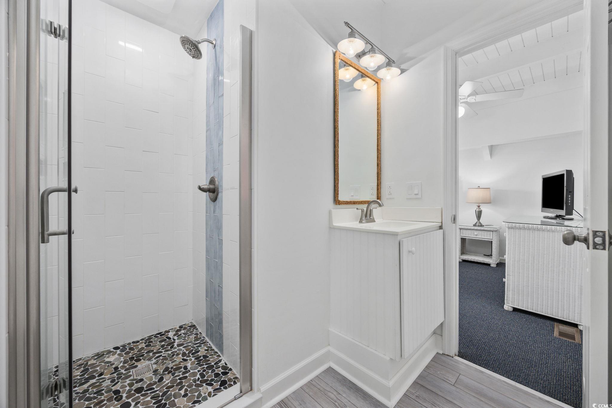 27 Riptide Lane Pawleys Island, SC 29585 - Photo 23 of 40 Bathroom featuring a stall shower, vanity, ensuite bathroom, and wood finished floors