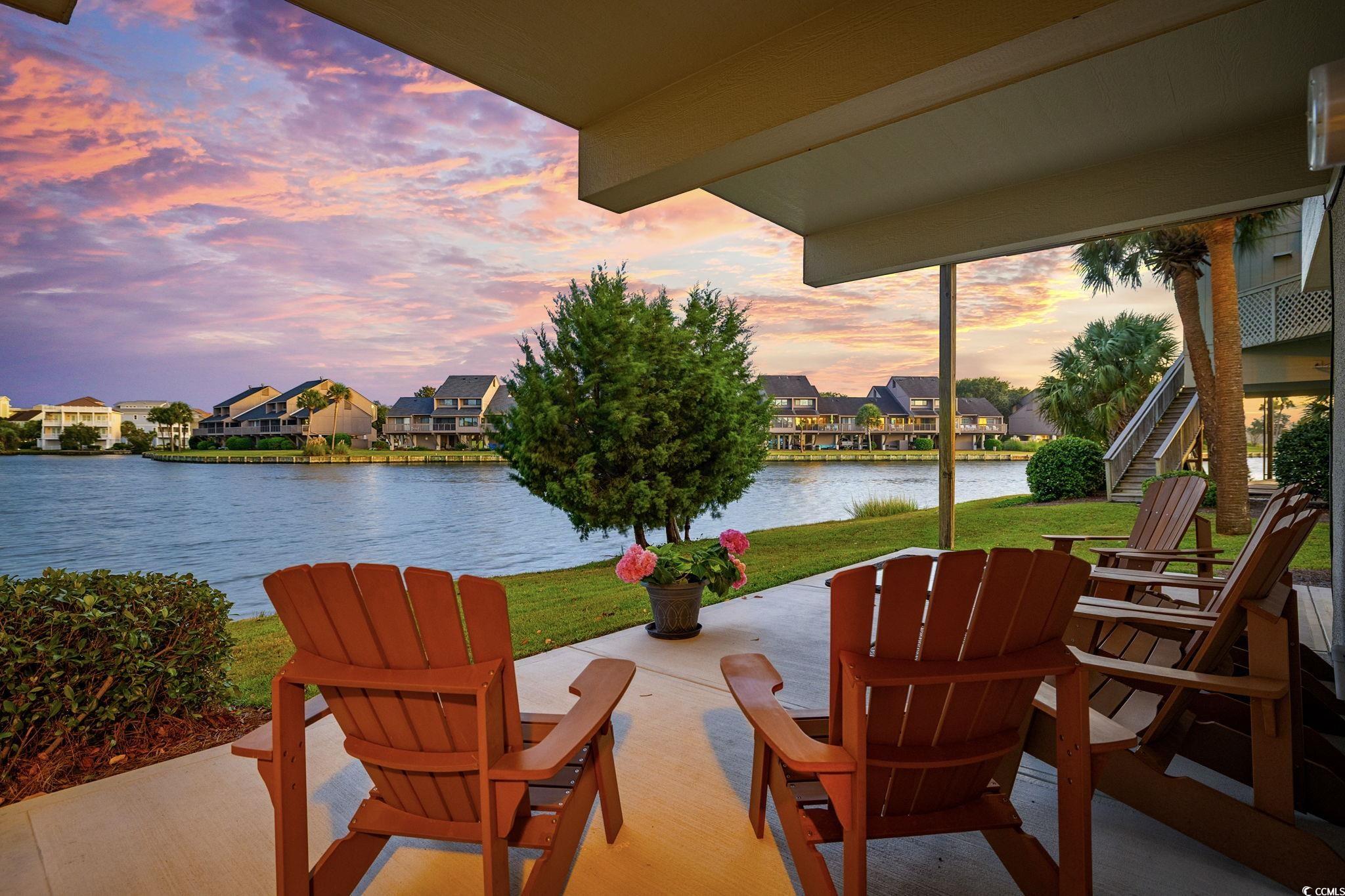 27 Riptide Lane Pawleys Island, SC 29585 - Photo 34 of 40 Patio terrace at dusk featuring a patio area, a yard, a water view, stairway, and a residential view