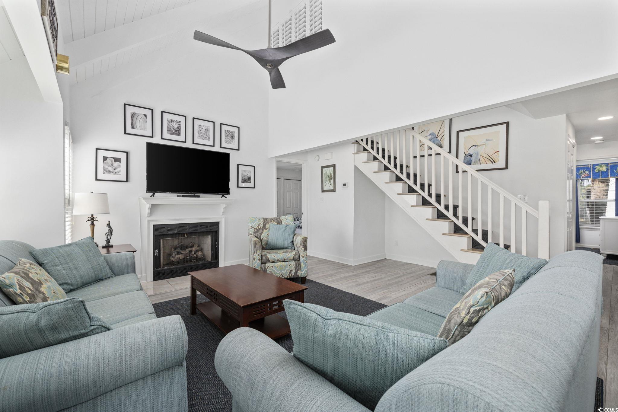 27 Riptide Lane Pawleys Island, SC 29585 - Photo 6 of 40 Living area with a fireplace, stairs, beam ceiling, wood finished floors, and high vaulted ceiling