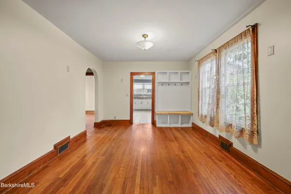a view of an empty room with a window and wooden floor