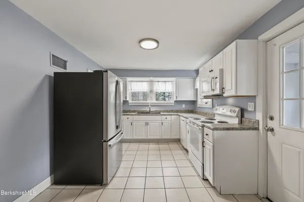 a kitchen with a refrigerator and white cabinets