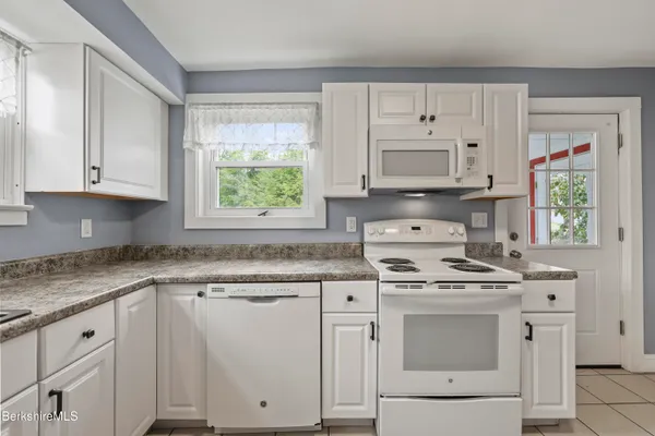a kitchen with granite countertop white cabinets and white stainless steel appliances