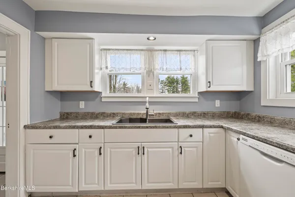 a kitchen with granite countertop white cabinets and a window