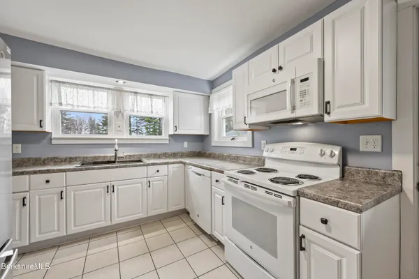 a kitchen with granite countertop white cabinets and a sink