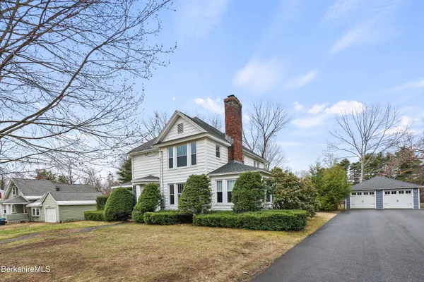 a front view of a house with a yard and trees