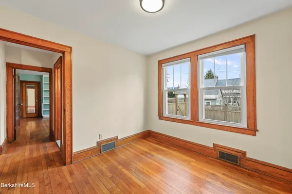 a view of an empty room with wooden floor and a window