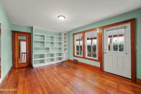 an empty room with wooden floor and windows