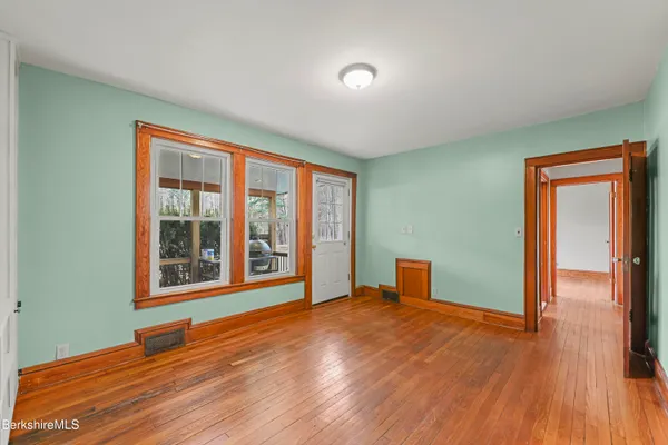 a view of an empty room with wooden floor and a window