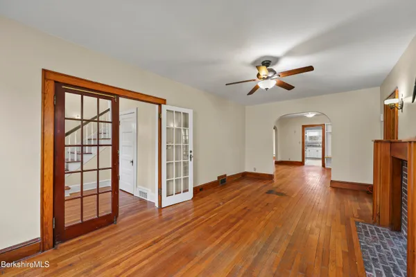 a view of empty room with wooden floor and fan