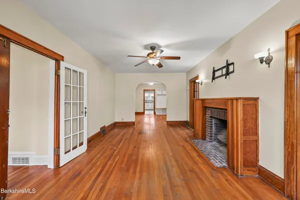 a view of a livingroom with wooden floor a ceiling fan and windows