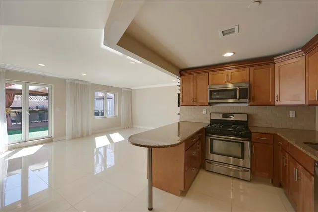 a kitchen with granite countertop stainless steel appliances a stove sink microwave and cabinets