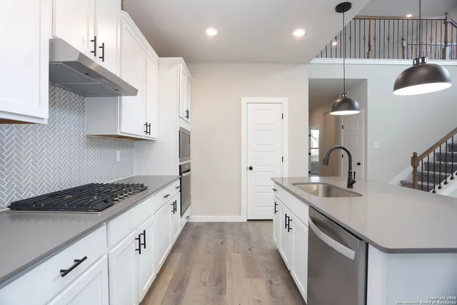 a kitchen with kitchen island stainless steel appliances a sink a stove and a wooden floors