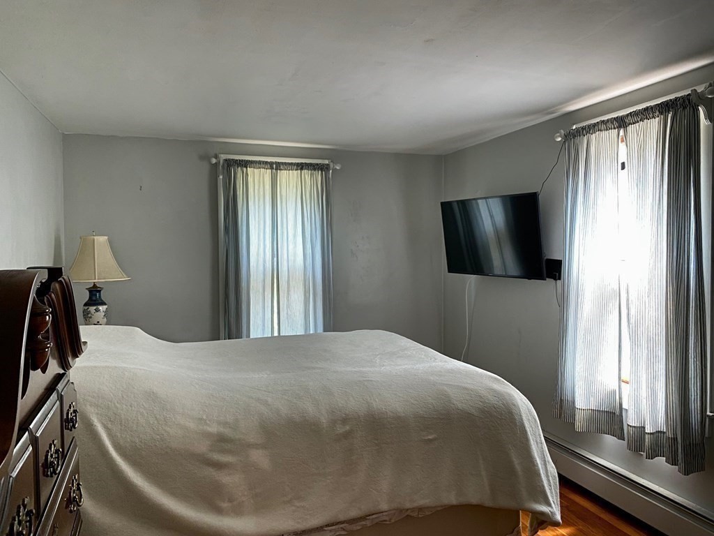 103 Clapp Road Scituate, MA 02066 - Photo 14 of 27 a bedroom with a bed and a flat tv screen on the dresser