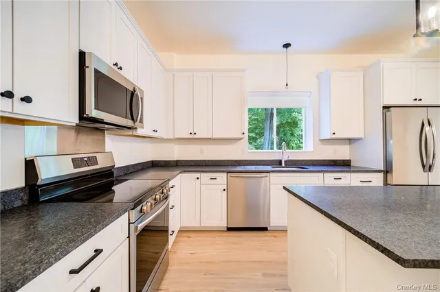 a kitchen with stainless steel appliances granite countertop a sink a stove and a microwave