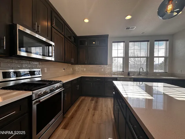 a kitchen with stainless steel appliances granite countertop a stove a sink and a microwave