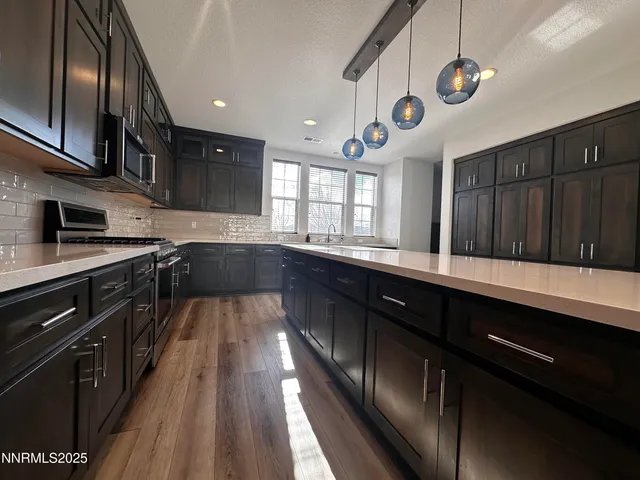a kitchen with stainless steel appliances granite countertop a sink wooden cabinets and wooden floor