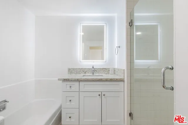 a bathroom with a granite countertop sink a mirror and a bathtub