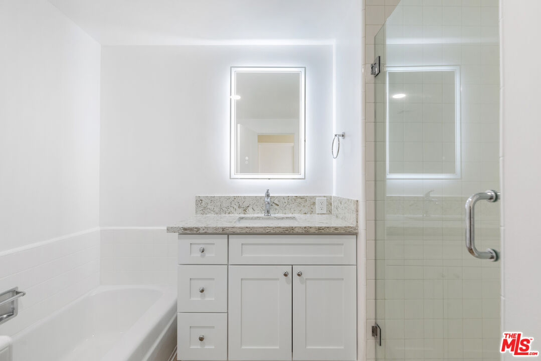 4455 Los Feliz Boulevard, Unit 1005 Los Angeles, CA 90027 - Photo 15 of 17 a bathroom with a granite countertop sink a mirror and a bathtub
