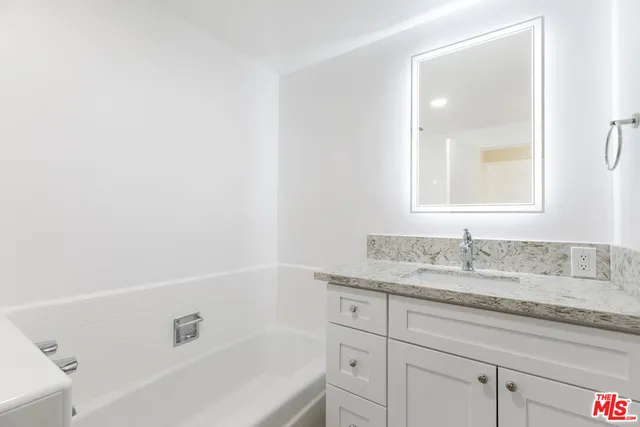 a bathroom with a granite countertop sink and a bathtub