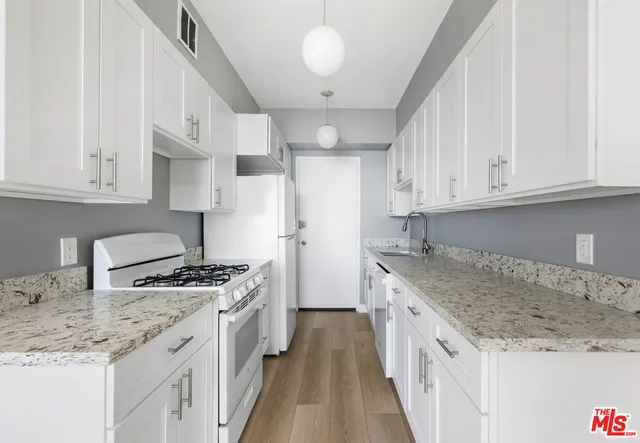 a kitchen with stainless steel appliances granite countertop a stove and a white cabinets