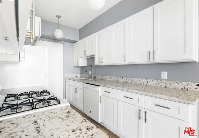 a kitchen with granite countertop a stove sink and cabinets
