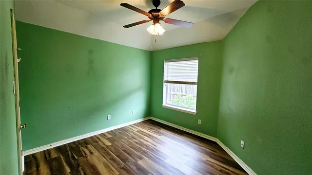 a view of a room with a ceiling fan and hardwood floor