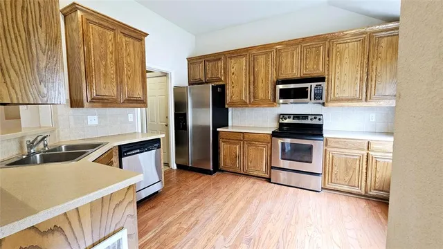 a kitchen with granite countertop a stove a sink dishwasher a refrigerator and cabinets with wooden floor
