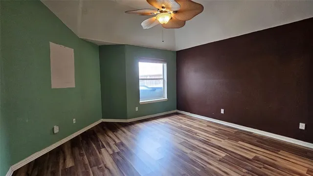 a view of an empty room with window and wooden floor