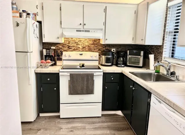 a kitchen with stainless steel appliances granite countertop a refrigerator a stove and white cabinets