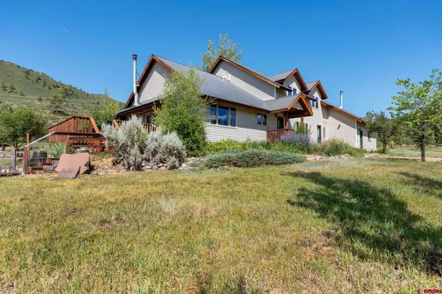 a view of a big house with a big yard and large tree