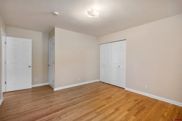 an empty room with wooden floor and bathroom view
