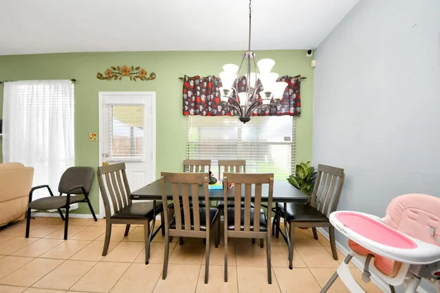 a view of a dining room with furniture a chandelier and a window