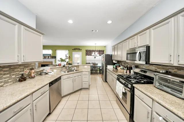 a large kitchen with stainless steel appliances granite countertop a lot of counter space and a sink