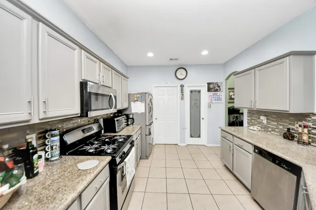 a kitchen with stainless steel appliances granite countertop a stove refrigerator sink and cabinets