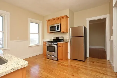 a kitchen with granite countertop a refrigerator and a stove top oven
