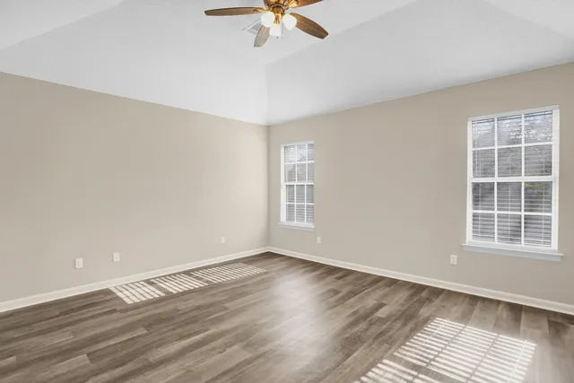 a view of an empty room with a window and wooden floor
