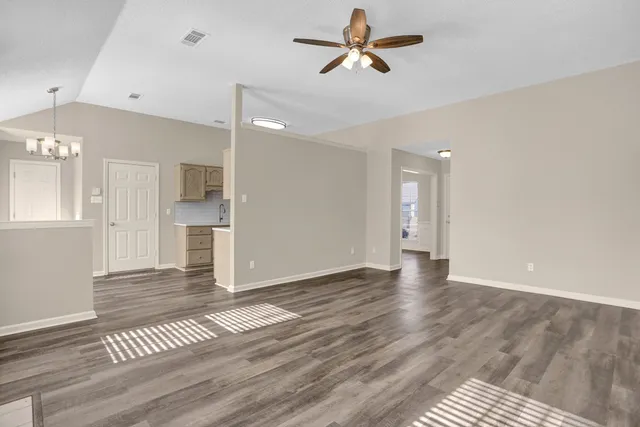a view of empty room with wooden floor and ceiling fan