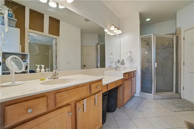 a bathroom with a granite countertop double vanity sink a mirror and a shower