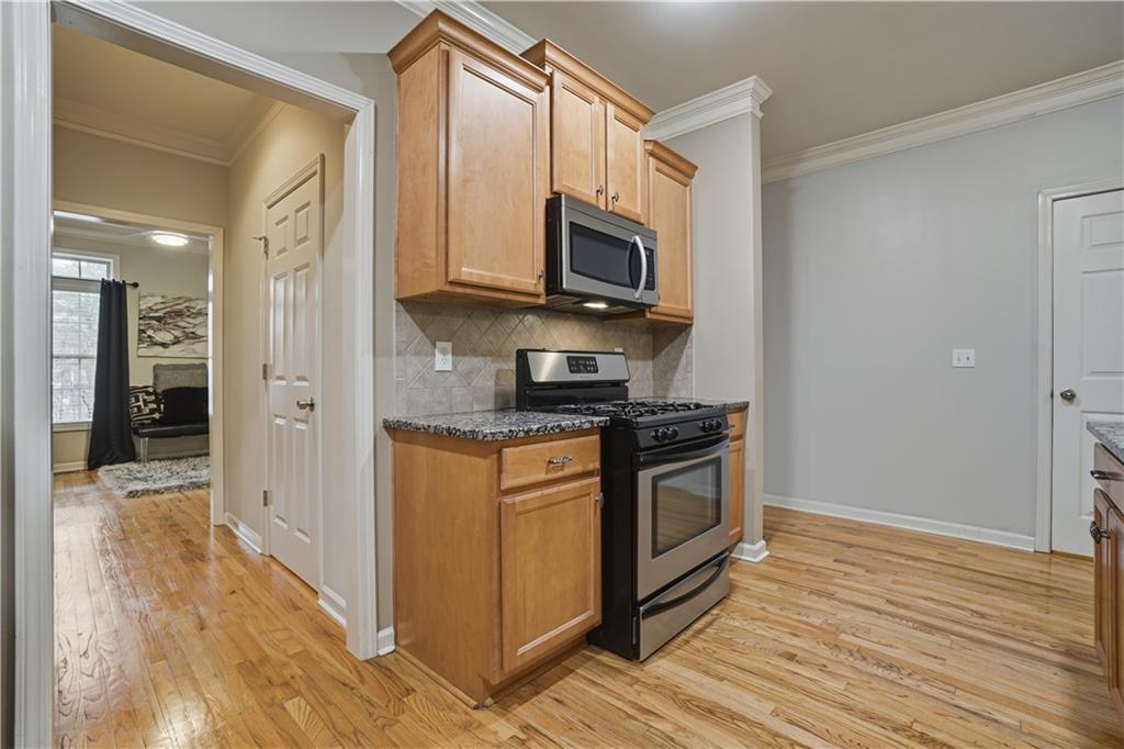 4414 George David Way Powder Springs, GA 30127 - Photo 6 of 29 a kitchen with stainless steel appliances granite countertop a stove top oven a sink and a granite counter tops with wooden floors